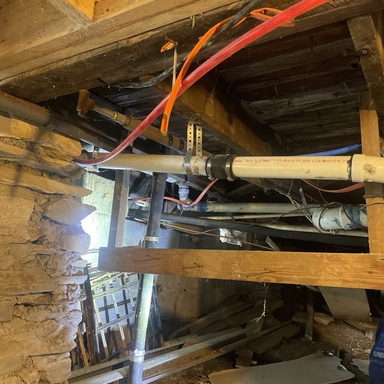 Older crawlspace with PEX and drain pipes under joists