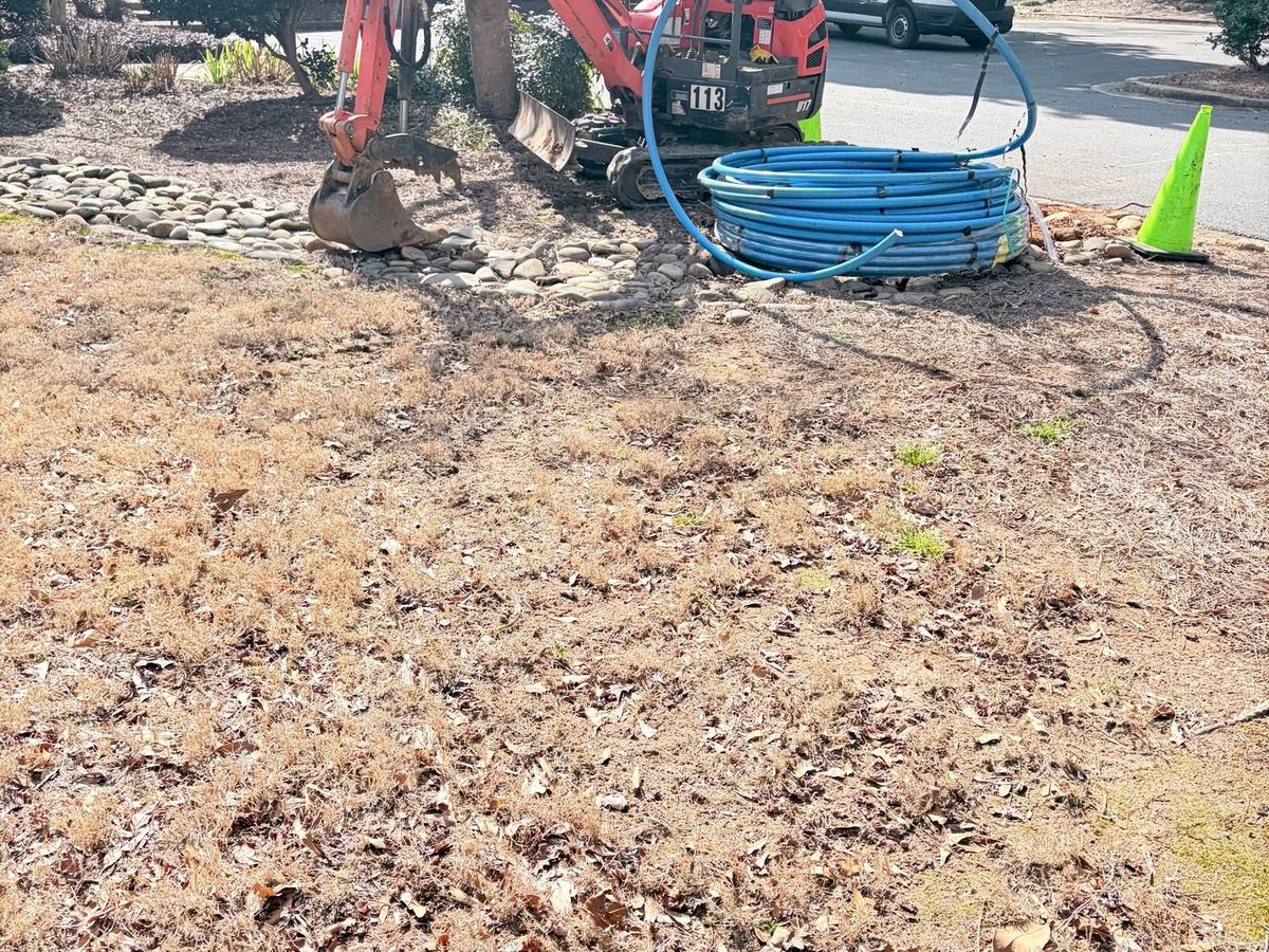 Red mini excavator and a coil of blue PEX water line
