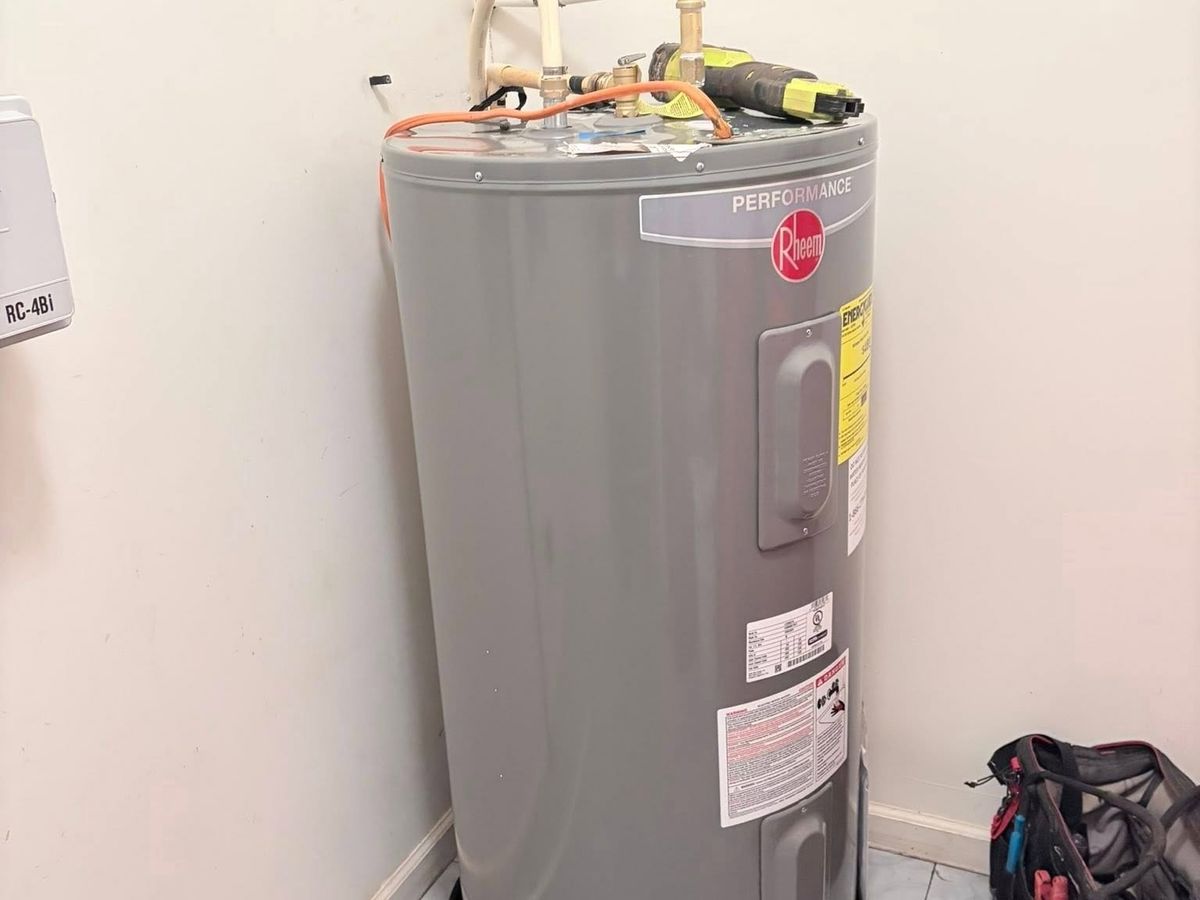 New gray electric tank water heater in a bathroom corner