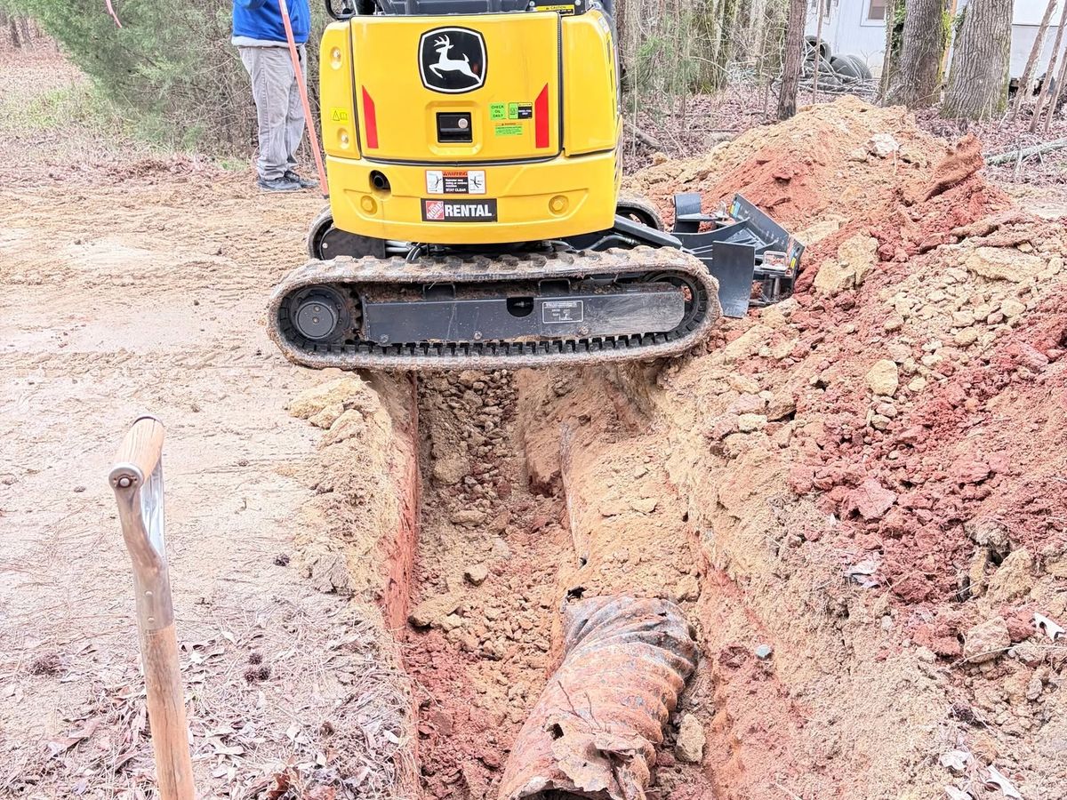 Yellow mini excavator parked over an open trench
