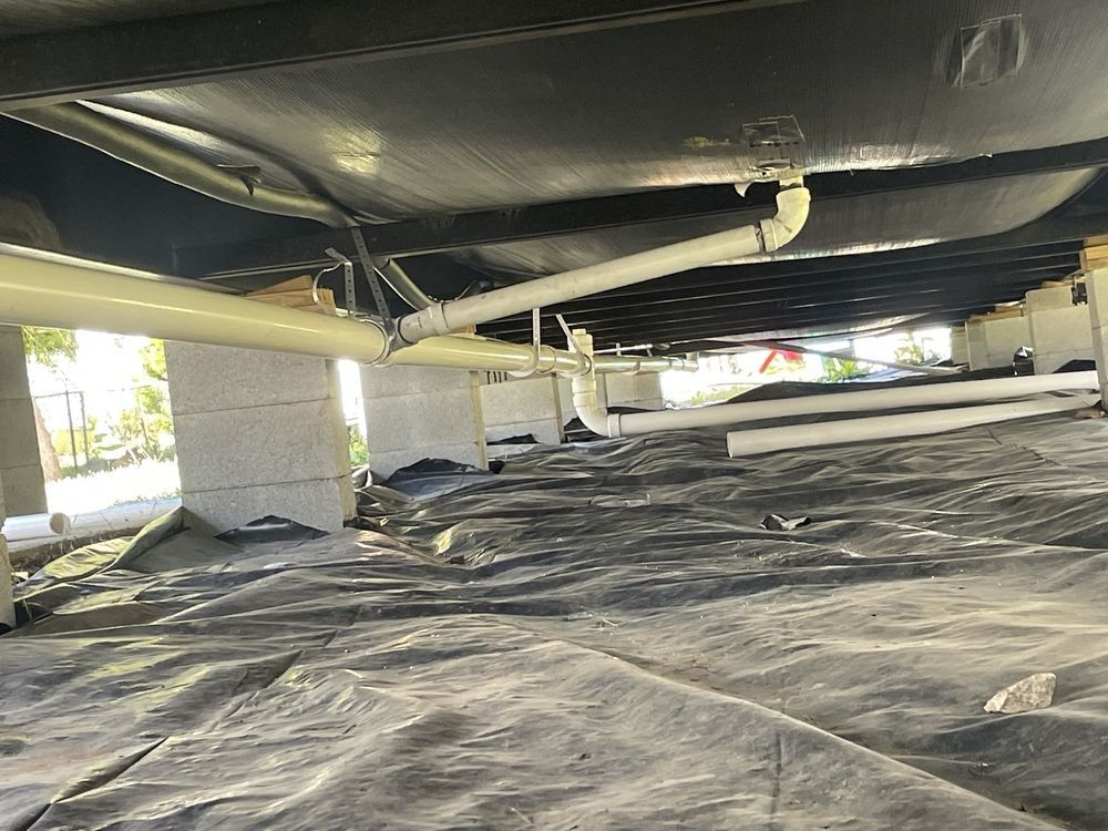 White PVC drain lines hanging beneath a floor