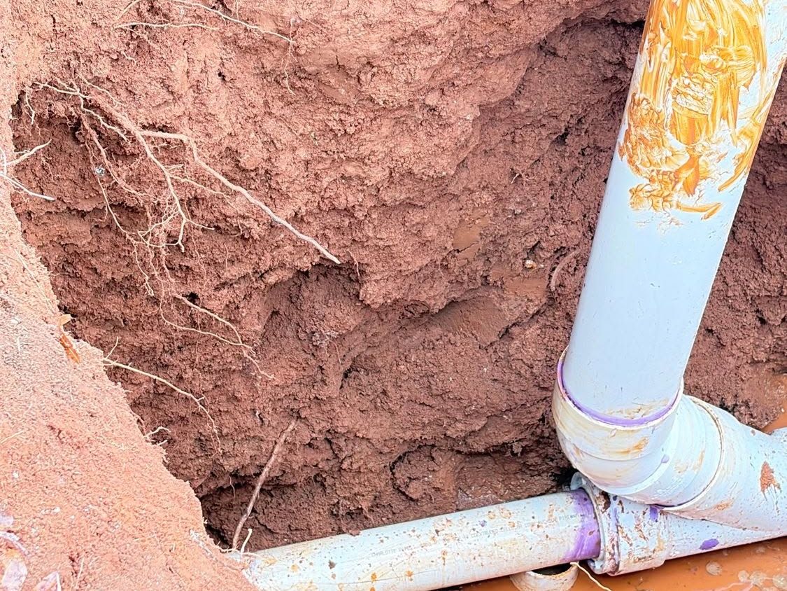 Red clay trench with gray sewer pipe and fittings