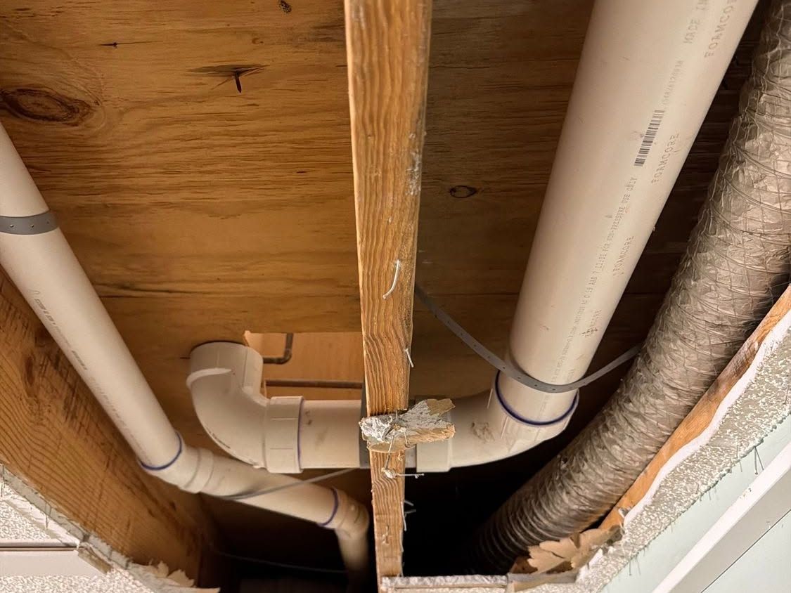 PVC drain lines under floor joists in an opened ceiling
