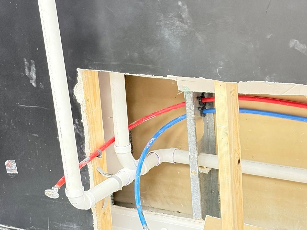 Opened wall with white PVC drain lines