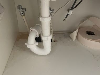 White PVC p-trap and drain under a sink