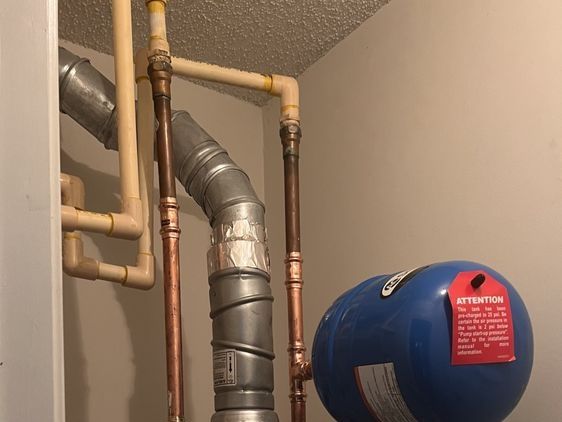 Blue pressure tank, copper pipes, and a flue in a closet