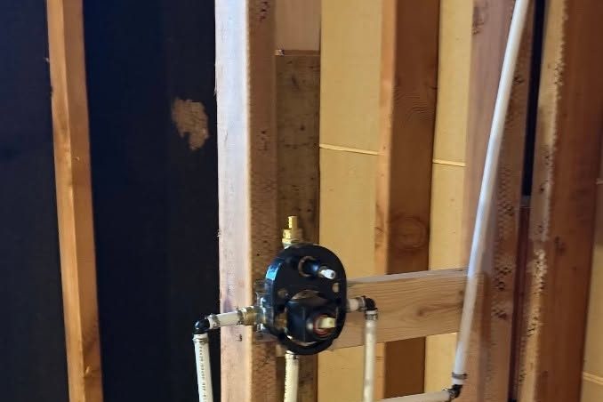 Shower valve body with PEX lines installed between framing studs in an open wall