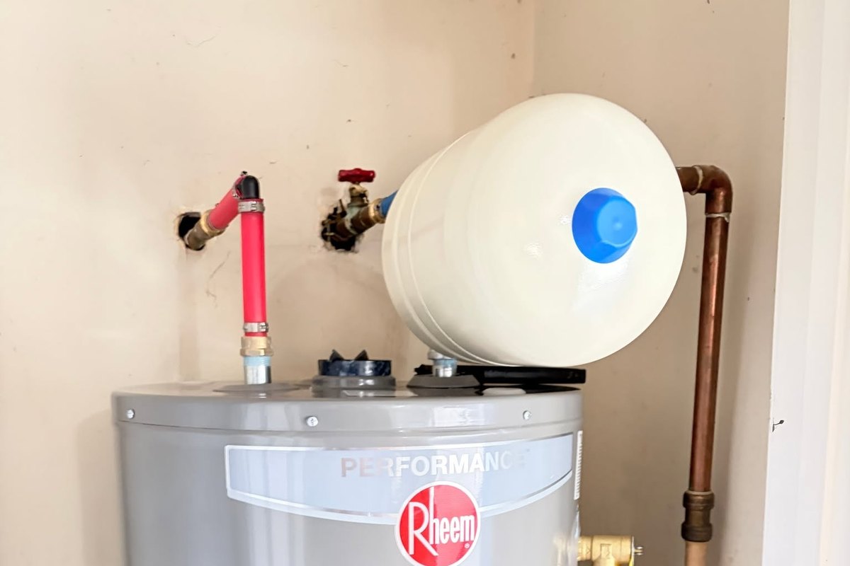 New gas tank water heater in a closet with an expansion tank and a copper water line