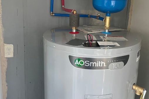 New electric tank water heater with blue and red PEX, a blue expansion tank, and flex conduit in a gray closet
